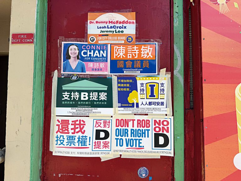 華埠一處門外貼有國會、市立大學校董會候選人及選票提案的中英文宣傳海報。記者蘇婕雅攝