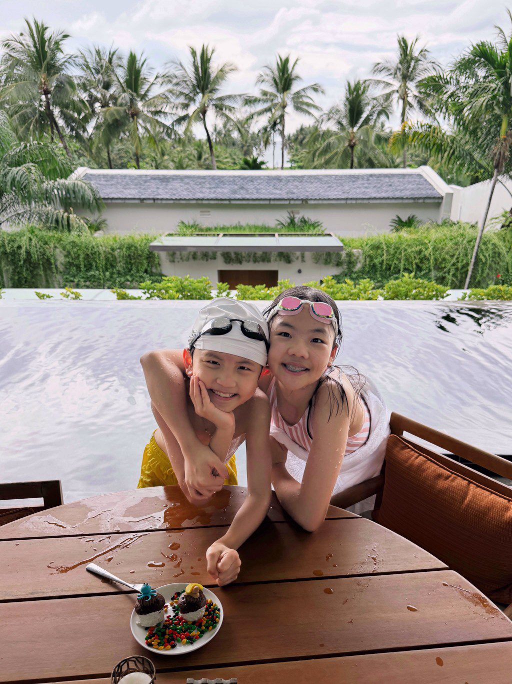 譚俊彥與任祉妍的子女在泳池邊貼頭合照，笑容可愛。