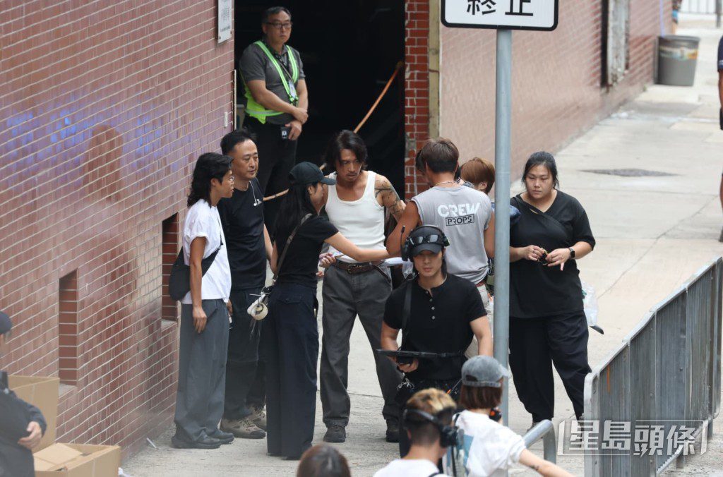 造型師抓緊時間為身穿背心的黃子華整理妝髮與服裝。