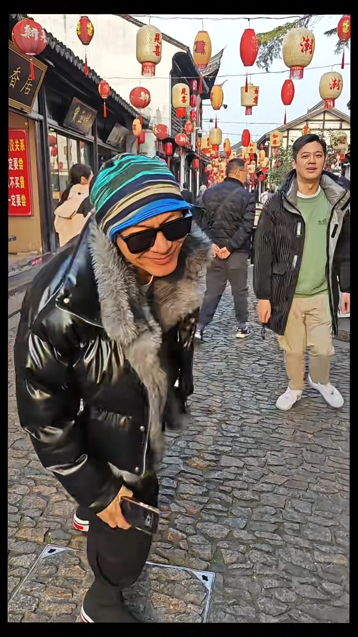 片中江華頭戴綠藍黃三色條紋冷帽及黑色毛毛羽絨,兒子陳耀淙則穿綠色衛衣及黑色羽絨外套。