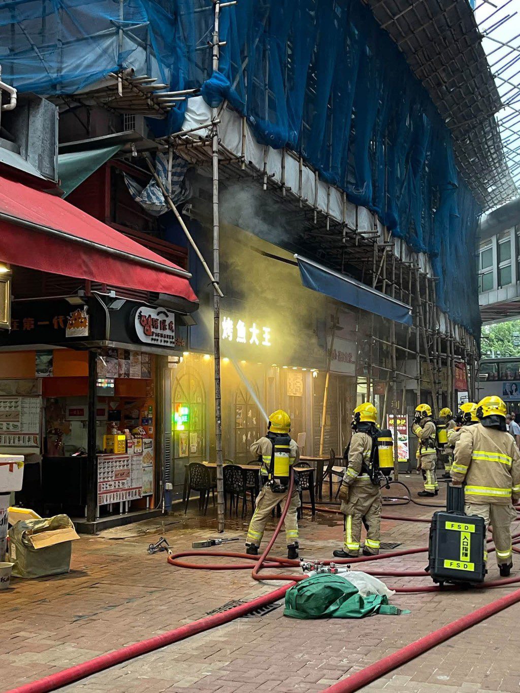 消防員向「烤魚大王」店內灑水,以控制火勢。